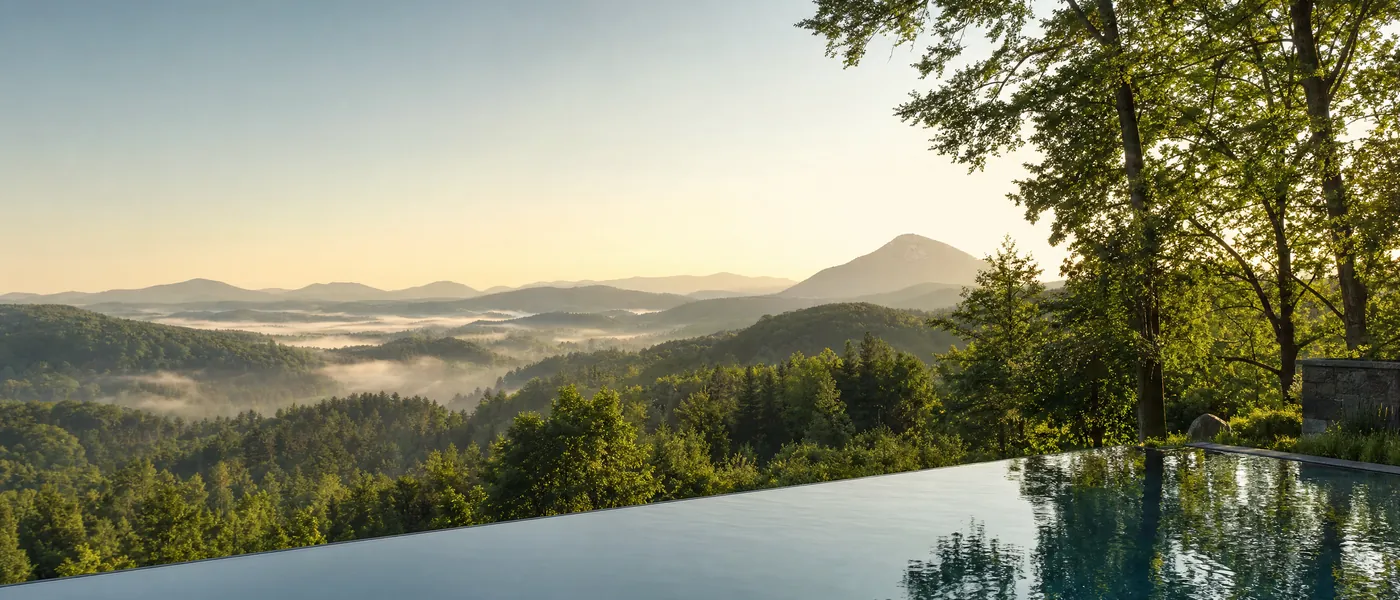 Morgennebel über bewaldeten Bergen bei Sonnenaufgang